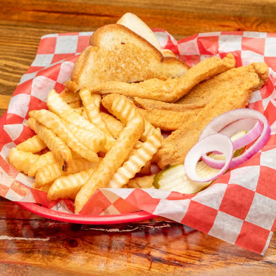Fried catfish, crinkle-cut fries, Texas toast, red onion, and pickles in a red basket.