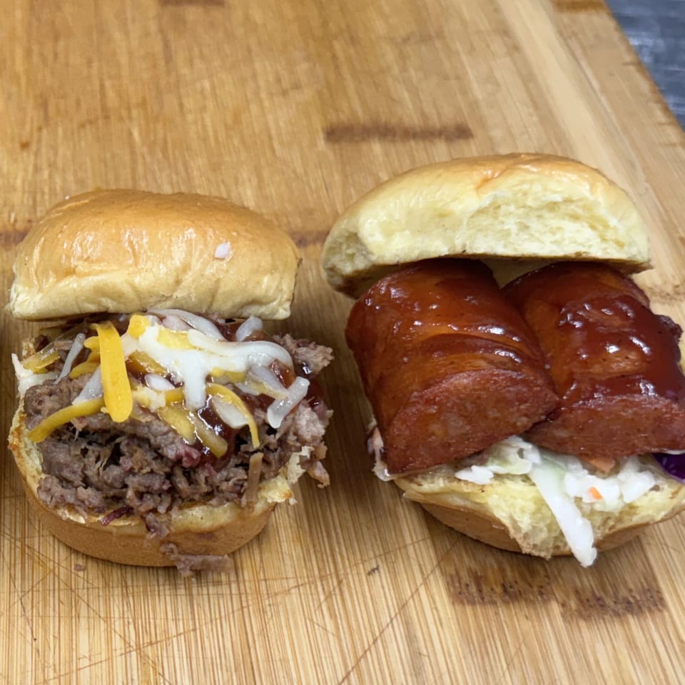 Two Southern BBQ Hilltop sliders: one with pulled pork and cheese, the other with sausage and coleslaw.