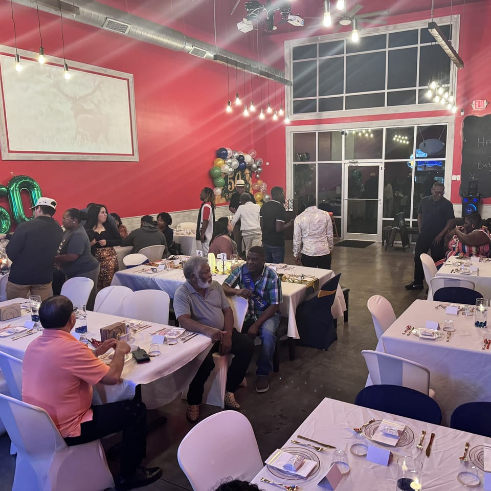 Guests mingle and sit at tables in a vibrant red Southern BBQ Hilltop dining room.