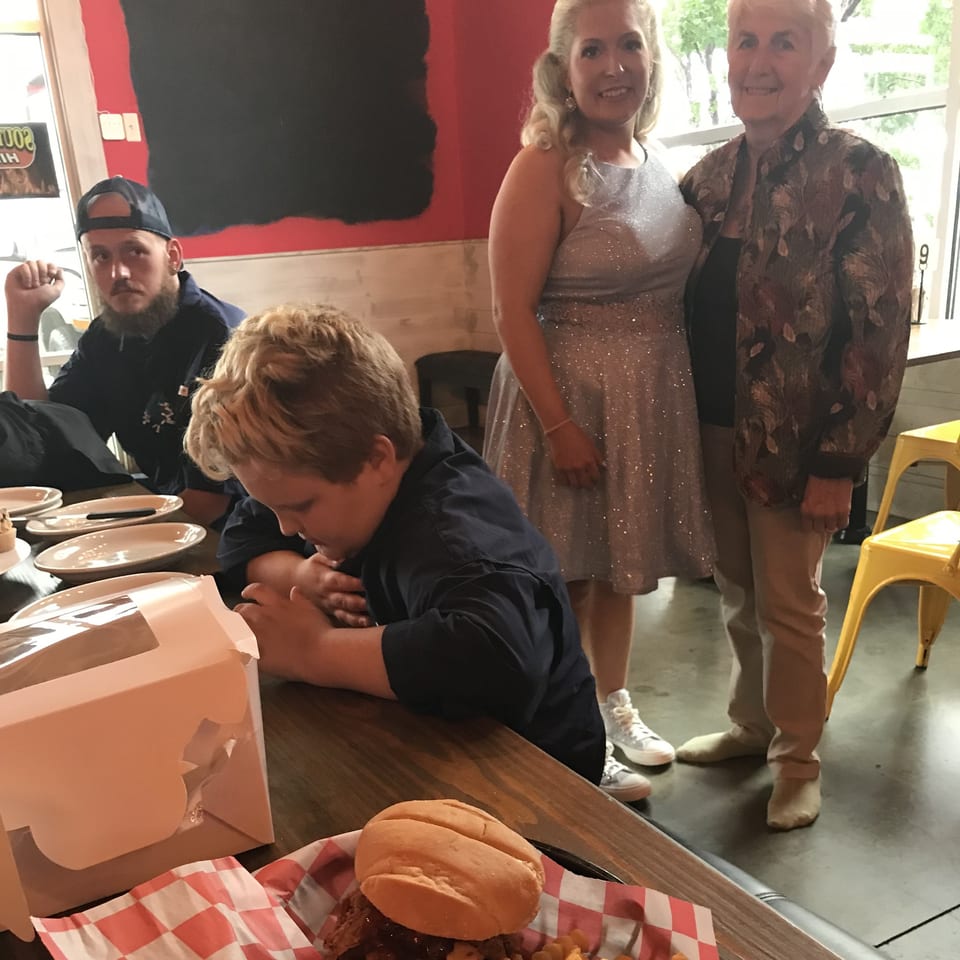 A family gathers around a table with a BBQ sandwich and fries at Southern BBQ Hilltop.